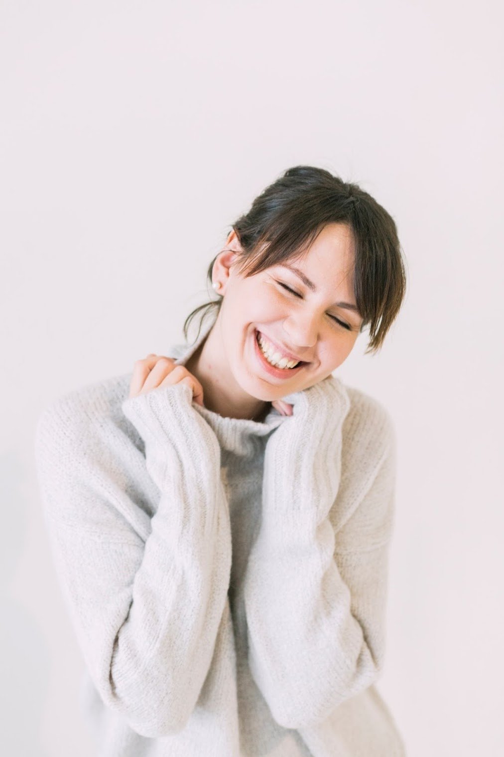 A middle-aged lady. She smiles with her eyes closed. Peaceful. Her teeth are showing. Her teeth are white. Someone who has had teeth whitening treatment before.