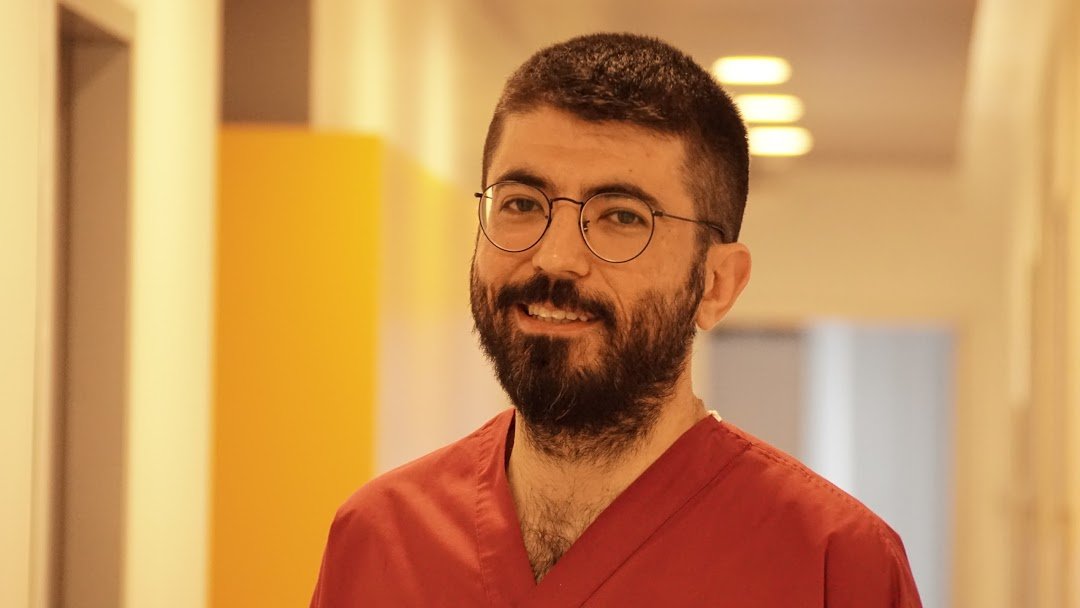 Gum doctor (Periodontologist) Çağdaş Çağlar Laçin. He's wearing an operation suit. Smiling.