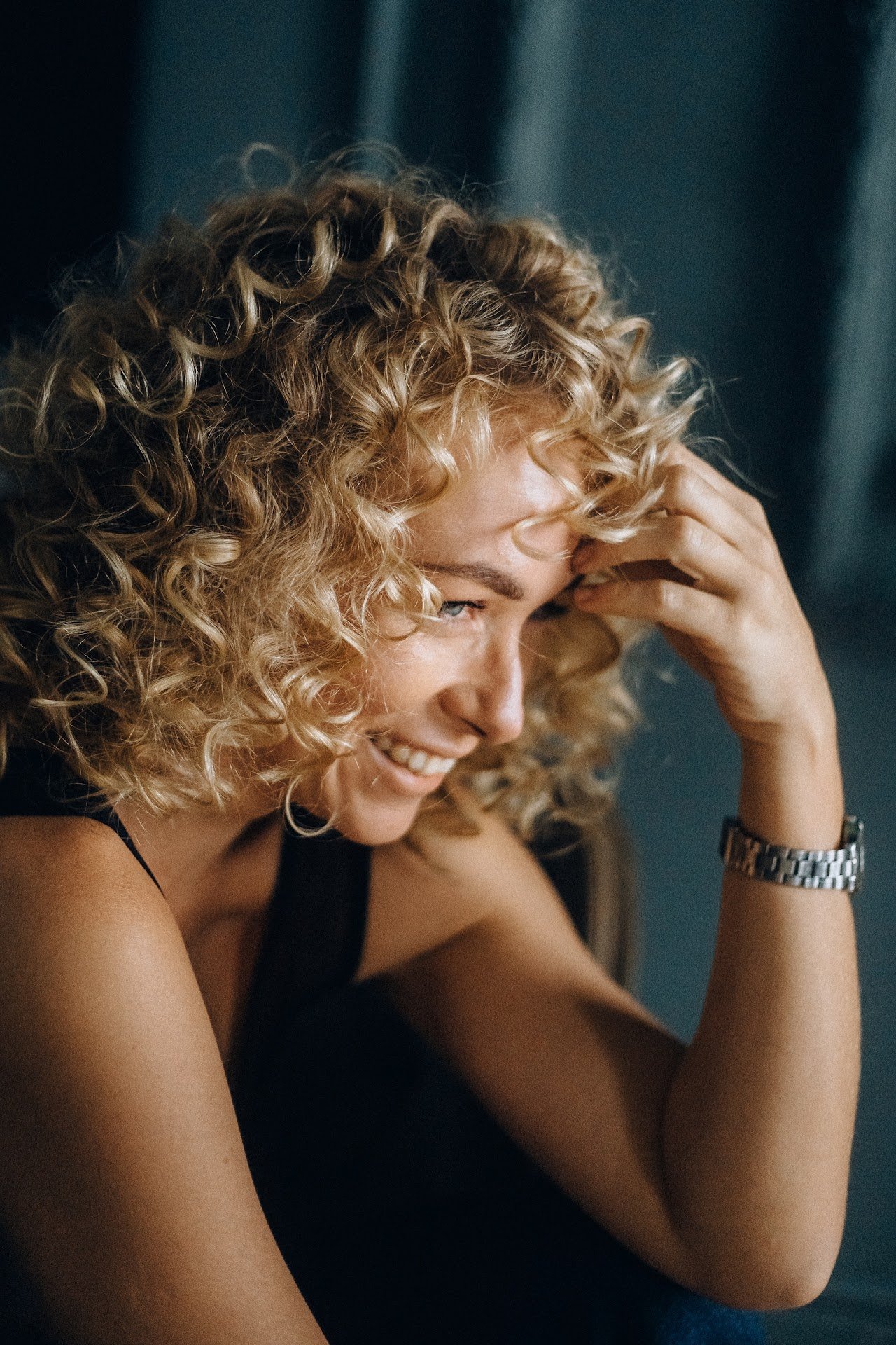 A curly-haired girl looks to her right and smiles.