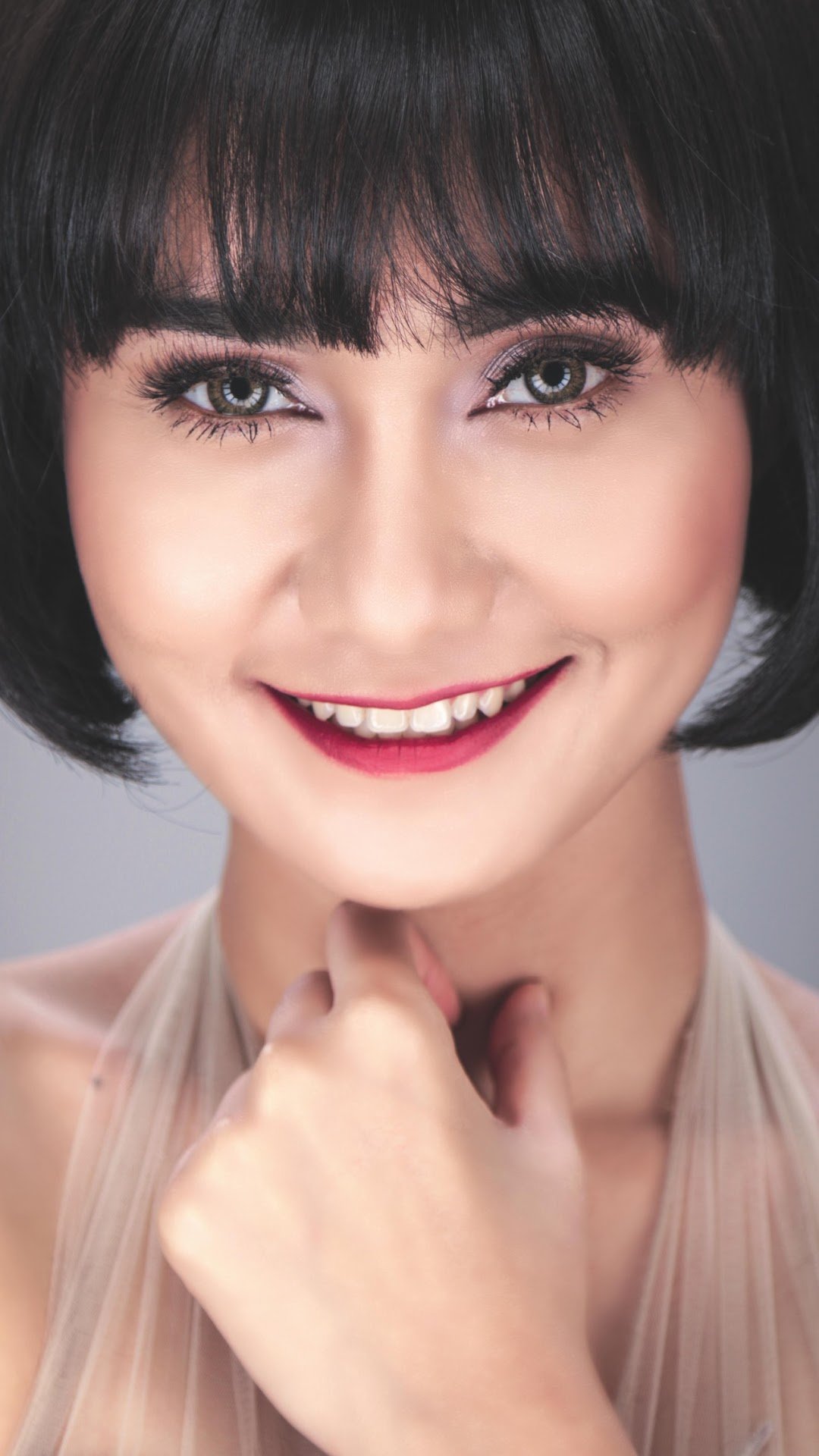 Beautiful woman face. Short hair. Smiling. Her upper teeth are visible. Someone who has had a Porcelain Lamina treatment.