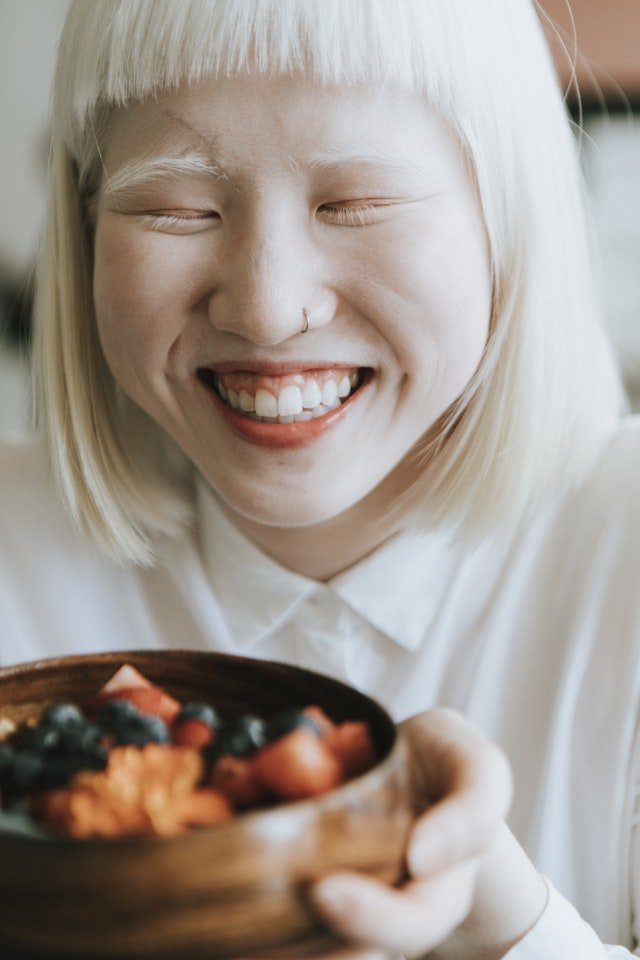 Young girl smiling with healthy gums and teeth. Light blonde hair.
