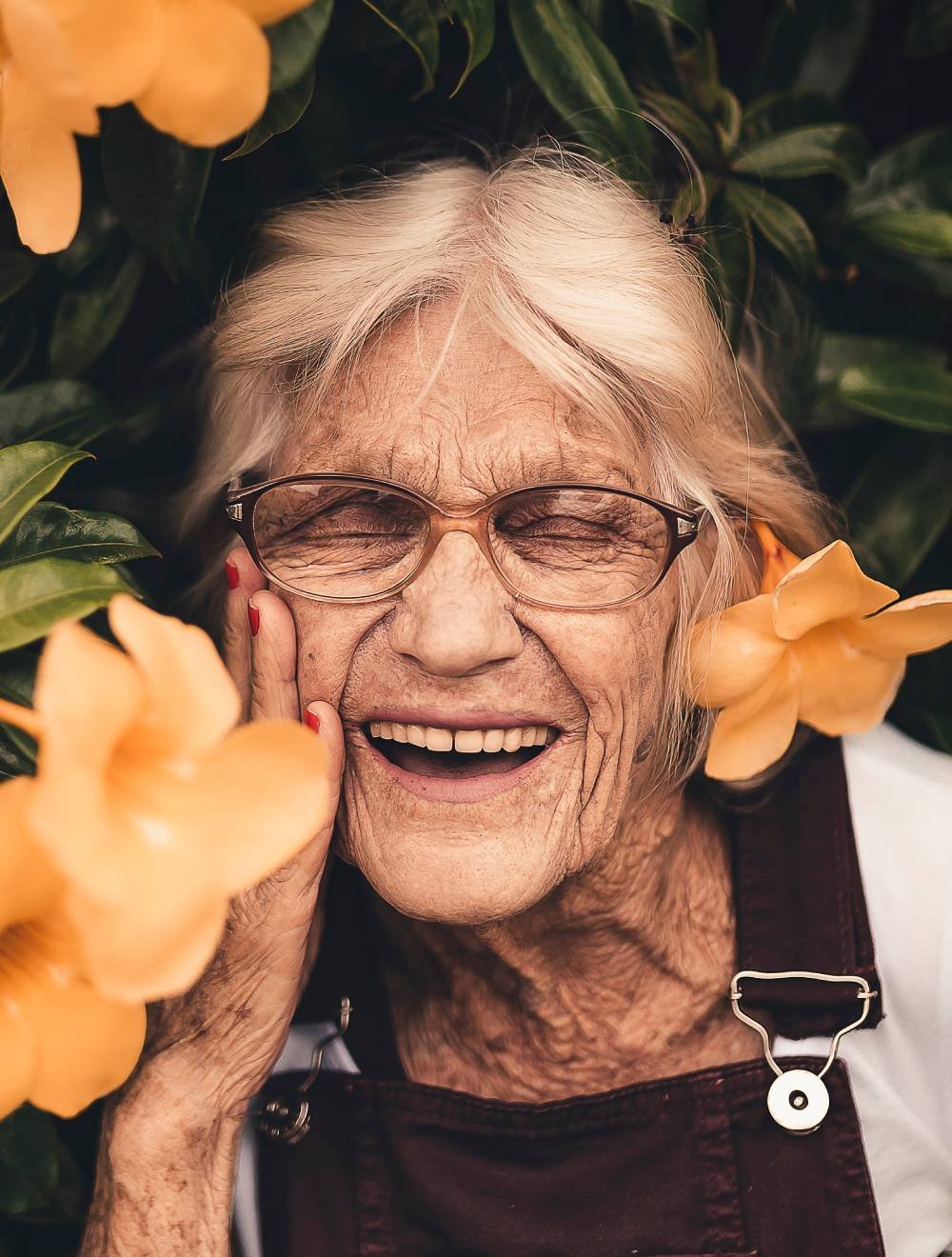 An old woman's face among the flowers. Smiling. Her teeth are strong and white. Someone who's been on All-on-4 treatment.