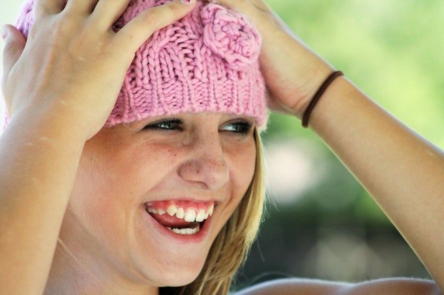 A young girl who had a gum graft operation. Wool beret on her head. Smiling.