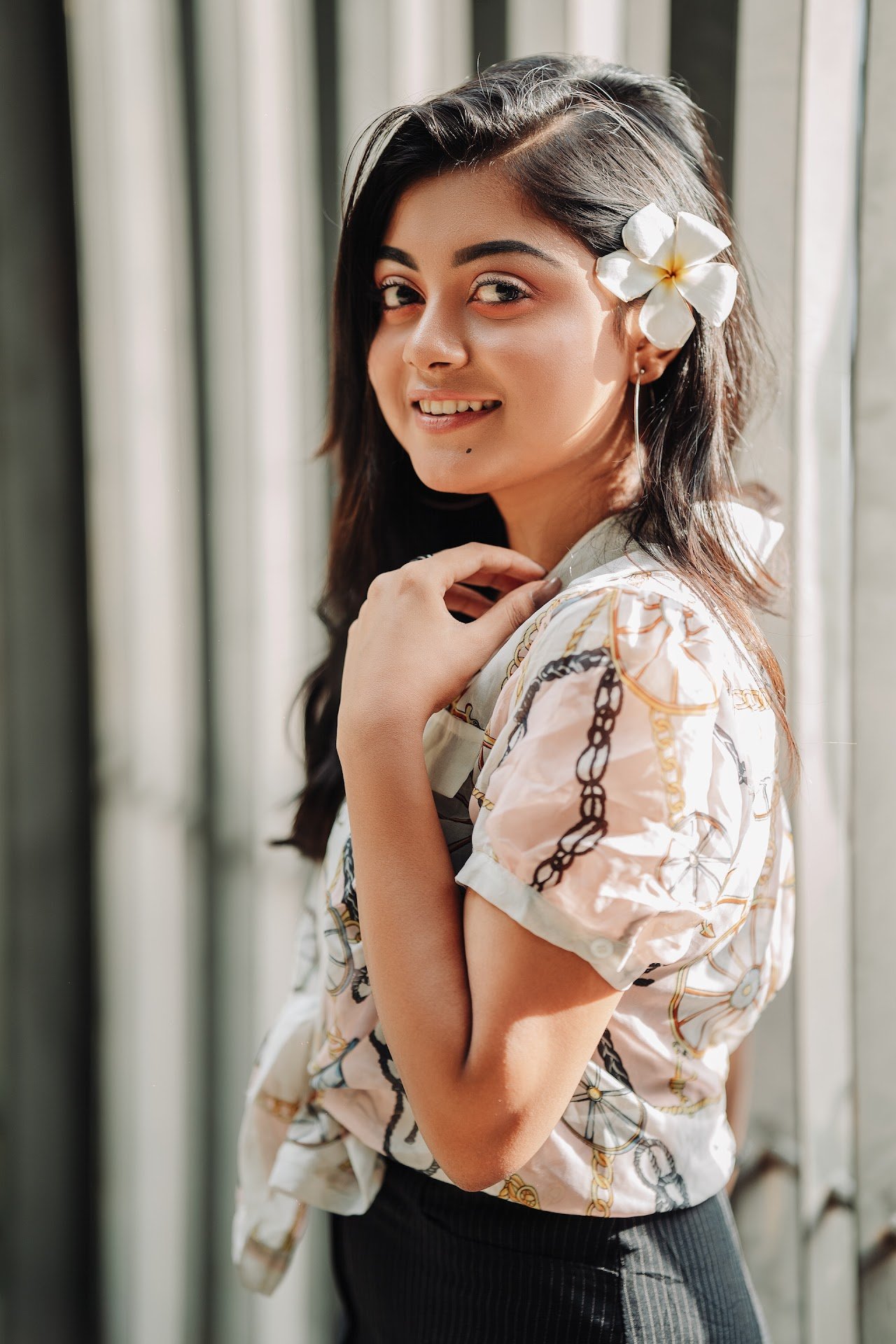 Close-up of a young girl wearing a flower in her ear, smiling.